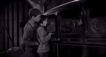 Movie still from “To Kill a Mockingbird” (1962), directed by Robert Mulligan – A young boy and a young girl looking out of an old car window; Medium shot, Over the shoulder angle