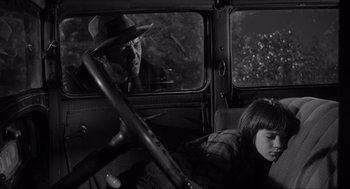 Movie still from “To Kill a Mockingbird” (1962), directed by Robert Mulligan – A black and white photo of a man and a woman in a car; Medium shot, Over the shoulder angle