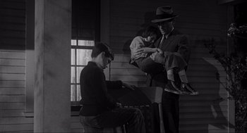 Movie still from “To Kill a Mockingbird” (1962), directed by Robert Mulligan – An old photo of a man and a boy playing piano; Wide shot, High angle