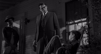 Movie still from “To Kill a Mockingbird” (1962), directed by Robert Mulligan – A man standing next to another man in a suit; Medium shot, Low angle
