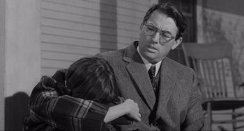 Movie still from “To Kill a Mockingbird” (1962), directed by Robert Mulligan – A man in a suit is hugging a woman; Medium shot, Over the shoulder angle