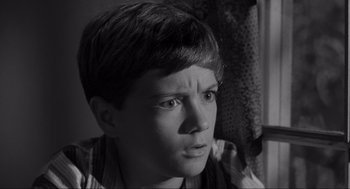 Movie still from “To Kill a Mockingbird” (1962), directed by Robert Mulligan – A young boy looking at the camera in a black and white photo; Close Up shot, High angle