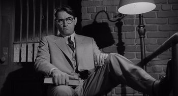 Movie still from “To Kill a Mockingbird” (1962), directed by Robert Mulligan – A black and white photo of a man sitting in a chair; Medium shot, Low angle