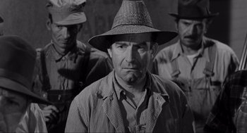 Movie still from “To Kill a Mockingbird” (1962), directed by Robert Mulligan – A man with a hat is standing in front of other men; Medium shot, Low angle