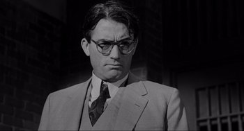 Movie still from “To Kill a Mockingbird” (1962), directed by Robert Mulligan – A man wearing a suit and tie with glasses; Close Up shot, Low angle
