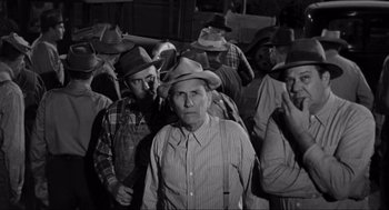 Movie still from “To Kill a Mockingbird” (1962), directed by Robert Mulligan – A group of men standing next to each other wearing cowboy hats; Medium shot, High angle