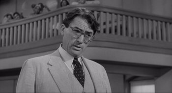Movie still from “To Kill a Mockingbird” (1962), directed by Robert Mulligan – A man in a suit and tie standing in front of a balcony; Close Up shot, Over the shoulder angle