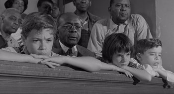 Movie still from “To Kill a Mockingbird” (1962), directed by Robert Mulligan – A black and white photo of a group of people sitting together; Medium shot, High angle