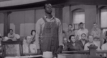 Movie still from “To Kill a Mockingbird” (1962), directed by Robert Mulligan – A black man in an apron standing in front of a group of people; Medium shot, Low angle