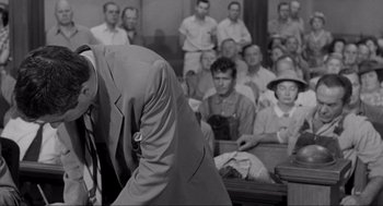 Movie still from “To Kill a Mockingbird” (1962), directed by Robert Mulligan – An old photo of a man standing in front of a crowd; Medium shot, High angle