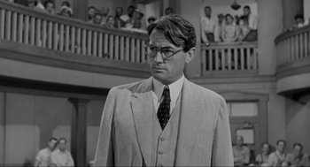 Movie still from “To Kill a Mockingbird” (1962), directed by Robert Mulligan – A man wearing a suit and tie standing in front of a crowd of onlookers; Medium shot, Over the shoulder angle
