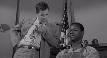 Movie still from “To Kill a Mockingbird” (1962), directed by Robert Mulligan – A man in a suit and tie standing next to another man in an overalls; Medium shot, Low angle