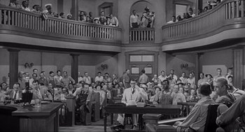 Movie still from “To Kill a Mockingbird” (1962), directed by Robert Mulligan – A group of people sitting in a large room; Wide shot, High angle