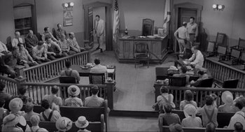 Movie still from “To Kill a Mockingbird” (1962), directed by Robert Mulligan – An old court room with people sitting in chairs; Wide shot, High angle