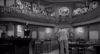 Movie still from “To Kill a Mockingbird” (1962), directed by Robert Mulligan – An old photo of a man in a court room; Wide shot, High angle