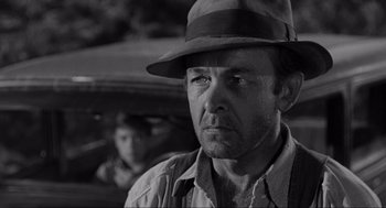 Movie still from “To Kill a Mockingbird” (1962), directed by Robert Mulligan – A man wearing a hat standing in front of a car; Close Up shot, Over the shoulder angle