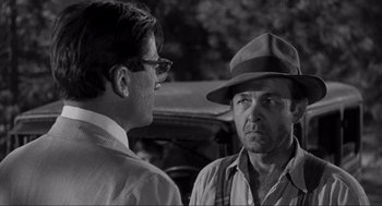 Movie still from “To Kill a Mockingbird” (1962), directed by Robert Mulligan – A man wearing a hat talking to another man in front of an old car; Close Up shot, Over the shoulder angle