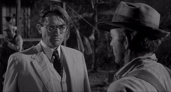 Movie still from “To Kill a Mockingbird” (1962), directed by Robert Mulligan – A man wearing a suit and tie talking to another man wearing a hat and glasses; Close Up shot, Over the shoulder angle
