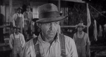 Movie still from “To Kill a Mockingbird” (1962), directed by Robert Mulligan – A man wearing a hat in a black and white photo; Close Up shot, Over the shoulder angle