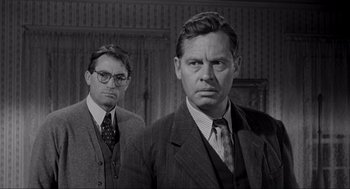 Movie still from “To Kill a Mockingbird” (1962), directed by Robert Mulligan – A man in a suit and tie standing next to another man in a suit and tie; Medium shot, Over the shoulder angle