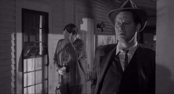 Movie still from “To Kill a Mockingbird” (1962), directed by Robert Mulligan – A man in a suit and a hat standing next to another man in a hat; Medium shot, Over the shoulder angle