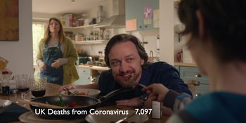 Movie still from “Together” (2021), directed by Justin Martin – A man sitting at a table with a plate of food in front of him; Medium shot, Over the shoulder angle