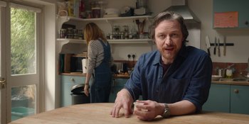 Movie still from “Together” (2021), directed by Justin Martin – A man sitting at a table in a kitchen; Medium shot, Low angle