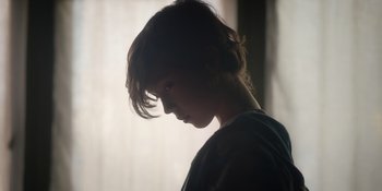 Movie still from “Together” (2021), directed by Justin Martin – A young woman is standing in front of a window; Close Up shot, Low angle