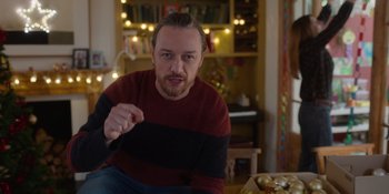 Movie still from “Together” (2021), directed by Justin Martin – A man sitting on the floor in front of some lights; Medium shot, Over the shoulder angle