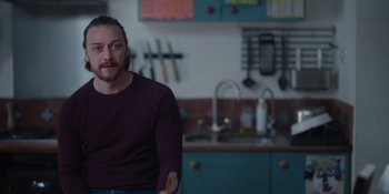 Movie still from “Together” (2021), directed by Justin Martin – A man sitting in front of a kitchen sink; Medium shot, Over the shoulder angle