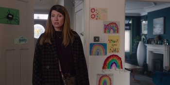Movie still from “Together” (2021), directed by Justin Martin – A woman standing in front of a white wall with rainbow pictures on the wall; Medium shot, Over the shoulder angle