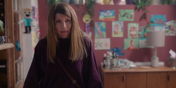 Movie still from “Together” (2021), directed by Justin Martin – A woman standing in front of a wall covered with pictures; Medium shot, Over the shoulder angle