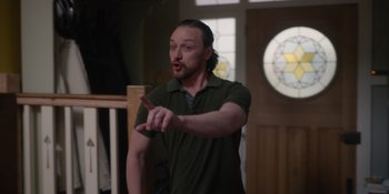 Movie still from “Together” (2021), directed by Justin Martin – A man standing in front of stained glass window; Medium shot, Over the shoulder angle