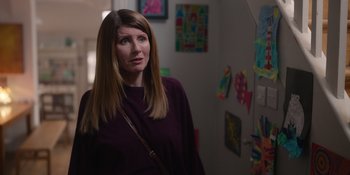 Movie still from “Together” (2021), directed by Justin Martin – A woman standing in front of a wall with pictures on the wall; Medium shot, Over the shoulder angle