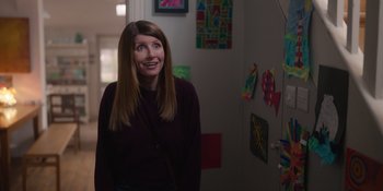 Movie still from “Together” (2021), directed by Justin Martin – A woman standing next to a wall with many pictures on the wall; Medium shot, Over the shoulder angle