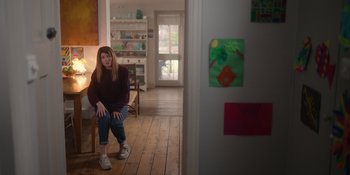 Movie still from “Together” (2021), directed by Justin Martin – A woman sitting on a chair in a living room; Wide shot, Low angle