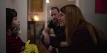 Movie still from “Together” (2021), directed by Justin Martin – A woman sitting next to a man in a room; Medium shot, Over the shoulder angle