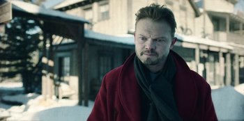 Movie still from “Togo” (2019), directed by Ericson Core – A man in a red coat is standing in the snow; Close Up shot, Over the shoulder angle