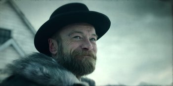 Movie still from “Togo” (2019), directed by Ericson Core – A man with a long beard wearing a hat and a fur coat; Close Up shot, Low angle