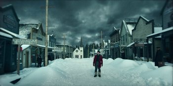 Movie still from “Togo” (2019), directed by Ericson Core – A man standing in the middle of a snow covered street; Extreme Wide shot, Low angle