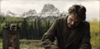 Movie still from “Togo” (2019), directed by Ericson Core – A woman in a brown coat standing in front of a mountain; Medium shot, Low angle