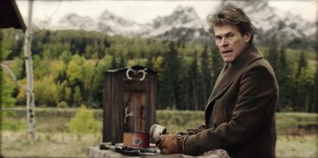 Movie still from “Togo” (2019), directed by Ericson Core – A man sitting at a table with a cup of coffee; Medium shot, Over the shoulder angle