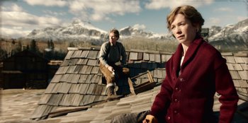 Movie still from “Togo” (2019), directed by Ericson Core – A man and a woman standing on top of a roof; Medium shot, Low angle
