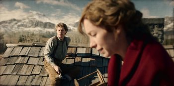 Movie still from “Togo” (2019), directed by Ericson Core – A man and a woman sitting on a wooden deck; Medium shot, Low angle