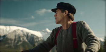 Movie still from “Togo” (2019), directed by Ericson Core – A man wearing a hat looking out at the mountains; Medium shot, Low angle