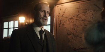 Movie still from “Togo” (2019), directed by Ericson Core – A man standing in front of a map; Close Up shot, Over the shoulder angle