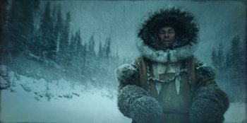 Movie still from “Togo” (2019), directed by Ericson Core – A man in a fur coat and a dog in the snow; Medium shot, Low angle