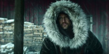 Movie still from “Togo” (2019), directed by Ericson Core – A man wearing a fur coat with a fur hood; Medium shot, Low angle