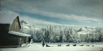 Movie still from “Togo” (2019), directed by Ericson Core – A man pulling a sled down a snow covered slope; Extreme Wide shot, High angle