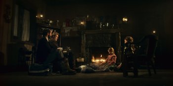 Movie still from “Togo” (2019), directed by Ericson Core – A group of people sitting in front of a fireplace; Wide shot, Over the shoulder angle